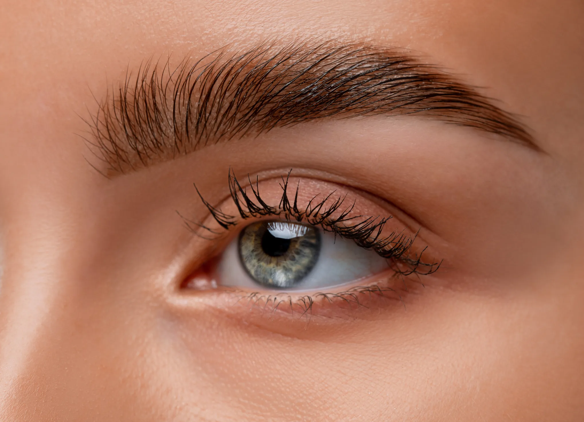 Close-up du regard mettant en valeur des sourcils naturels et une peau lumineuse dans un style esthétique doux